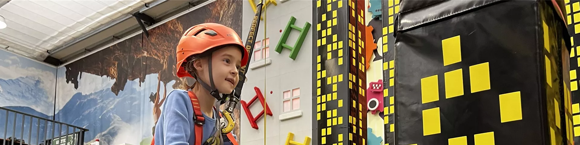 kind-klettert-in-der-kletterhalle-mit-helm